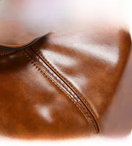 Dettaglio della doppia cucitura precisa sulla borsa a secchiello in pelle marrone vintage