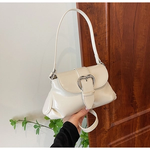 Close-up of cream saddle bag featuring a polished PU surface and heart-shaped metal buckle