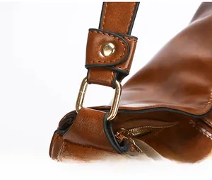 Dettaglio della fibbia a D in metallo resistente e della cerniera della borsa marrone