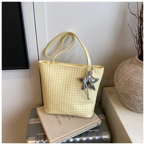 Detail view of woven leather texture on a yellow tote bag with a silver star charm