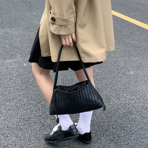 Detail einer handgewebten schwarzen Ledertasche, präsentiert von einem Model in urbanem Stil