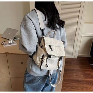 Detail view of beige nylon waterproof backpack featuring flap closure and multiple pockets