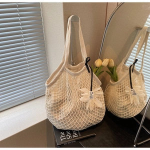 Close-up of white crochet mesh tote bag featuring inner fabric liner and floral charm