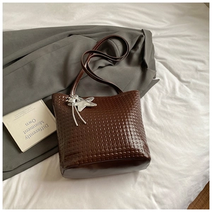 Detailed close-up of dark brown woven texture tote bag with star charm on white fabric
