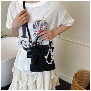 Detailed view of black pleated bucket bag with large pearl charm on a model