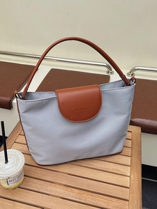 Chic grey-blue canvas tote bag with brown leather handles on a wooden table