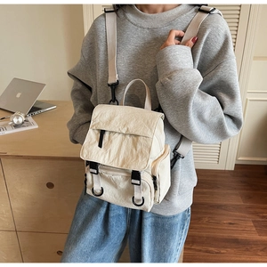 Close-up of cream canvas backpack featuring washed texture and functional buckle pockets