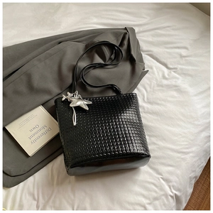 Close-up of black woven bucket bag texture with silver starfish pendant detail
