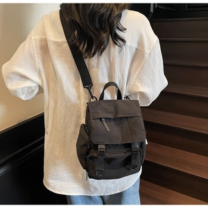 Detail of a black nylon crossbody bag with buckle closure and adjustable wide strap