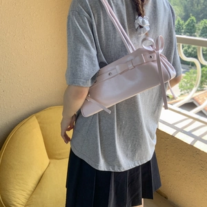 Detail of pink balletcore shoulder bag with bow ribbons and metal eyelet accents