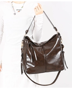 Dettaglio di borsa a secchiello in pelle marrone vintage con frange e tracolla regolabile