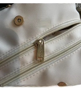 Détail du tissu en nylon blanc imperméable avec fermeture éclair dorée et boucle magnétique