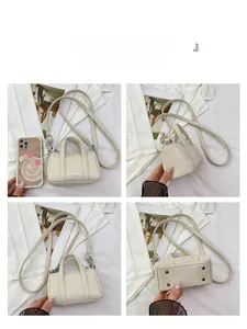 Detail view of mini off-white Boston bag with lychee grain texture and metal feet