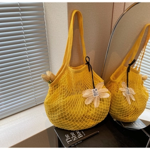 Detailed close-up of yellow knit mesh tote bag with white flower charm and inner lining