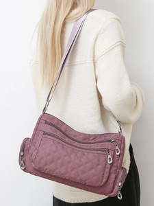Quilted nylon crossbody bag with multiple zip pockets shown on a female model