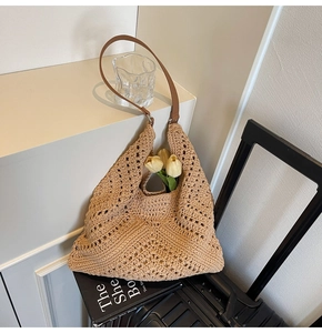 Detail der beige geflochtenen Tragetasche mit braunem Lederriemen und Häkelmuster