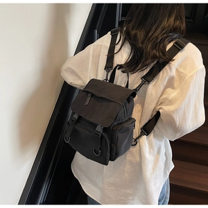 Side view of black canvas backpack showing multiple pockets and adjustable buckle straps