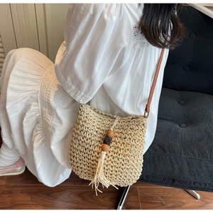 Dettaglio borsa a tracolla in paglia intrecciata con frange boho e perline di legno
