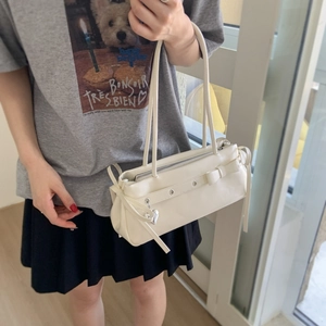 Detailed look at a white leather shoulder bag with bow and heart charm on a model
