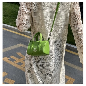 Chic green mini boston bag with lychee texture styled with a white lace dress in a street view