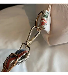 Détails des finitions métalliques dorées et de la bandoulière tissée colorée du sac à main