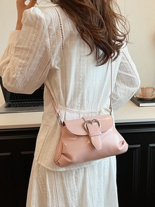 Pink patent leather saddle bag with heart buckle shown worn on white lace dress