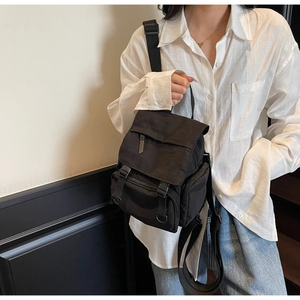 Close-up of black nylon mini backpack with flap buckles and adjustable straps