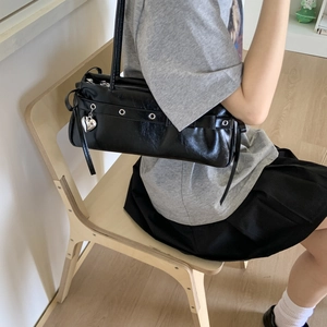 Detail of glossy black faux leather shoulder bag with silver heart charm and metal eyelets