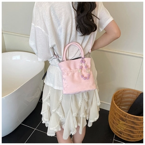 Detailed view of pink mini crossbody bag with woven texture and purple beaded accessory
