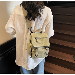 Detail view of khaki green nylon backpack with adjustable straps and multi-pocket design