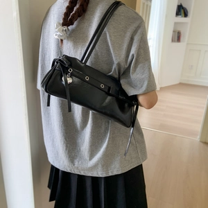 Detail of black glossy shoulder bag with silver eyelets and a silver heart charm