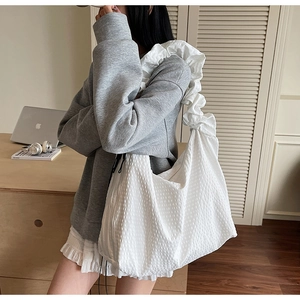 Close-up of white waffle texture tote bag with ruffled shoulder strap detail