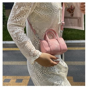 Detailed outdoor shot of a pink mini barrel crossbody bag with pebbled leather texture