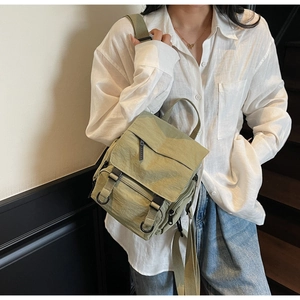 Detail of green nylon mini backpack with multiple zippered pockets and adjustable straps
