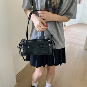 Close-up of black shoulder bag featuring a decorative bow and silver metal eyelets
