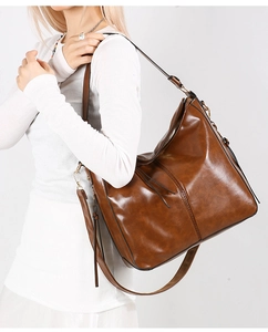 Dettaglio borsa tote marrone vintage con finitura in pelle lucida e nappa decorativa in pelle