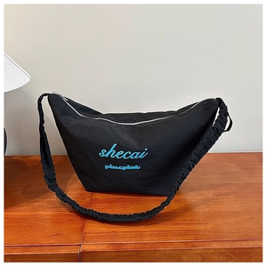 Detailed view of black crescent bag with blue embroidery and pleated shoulder strap design