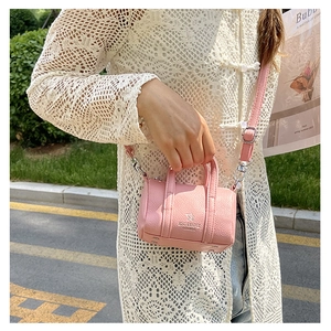 Close-up of pink litchi grain leather mini boston bag with adjustable shoulder strap
