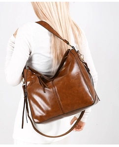 Dettaglio della borsa hobo marrone ambra con finitura lucida su modella femminile