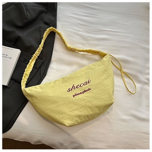 Detailed view of yellow hobo bag with pleated texture and embroidered branding letters