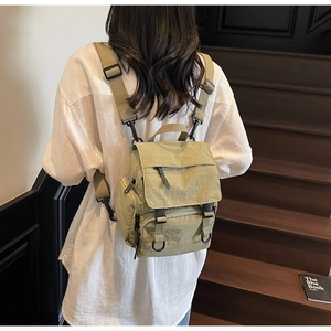 Detail view of khaki nylon backpack with multiple zipper pockets on wooden stairs