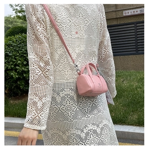 Detail shot of mini pink cylinder crossbody bag in pebble grain leather texture