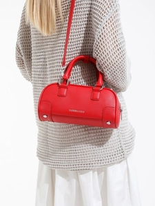 Sac bowling rouge en cuir grainé avec lettrage argenté porté par un mannequin