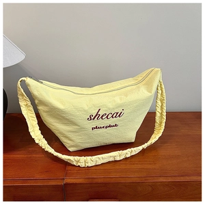 Detail of light yellow ruched shoulder bag with metallic zipper and printed graphics