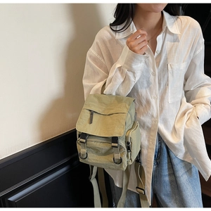Detail of an olive green nylon mini backpack featuring a flap cover and buckle closure