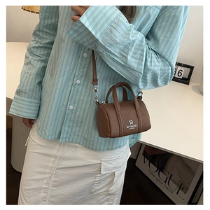 Detail of brown mini cylinder crossbody bag with star logo on textured faux leather