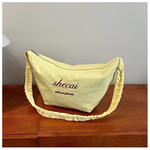 Detail of light yellow crescent bag with pleated fabric texture and red script logo
