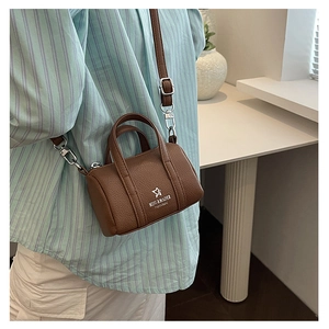 Close-up of brown pebbled leather mini cylinder bag with adjustable shoulder strap detail