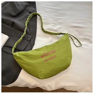 Detail of avocado green pleated crescent bag with pink embroidered lettering and soft texture