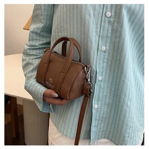 Close-up of a brown mini cylinder handbag with pebble leather texture and silver logo